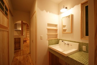 アールの入口を通るとグリーンのモザイクタイルが爽やかな造作洗面台があります