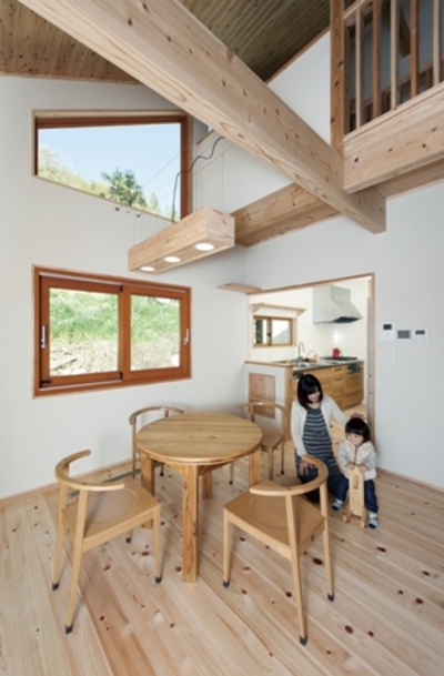 豊かな緑と青空に手が届きそうなほど身近に感じられるリビングルーム。木製サッシがまるで額縁のように景色を彩り、無垢材や塗り壁の室内と調和しています。