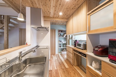 キッチンは両サイドから入れ、調理の手元が丸見えにならないようにレンジ台部分には壁をつくった。背面の収納は造作。