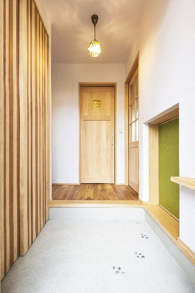 洗い出しの土間に玉石で足跡を演出したかわいい玄関ホール。緑色の戸は和室へ通じます。