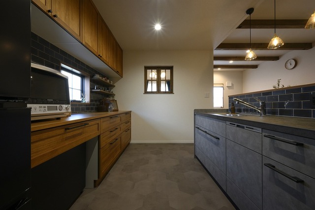 6帖のキッチンは、床を6角タイルにしリビングダイニングと貼り分けました。家電の色と合うように、キッチンはダークトーンに。そして収納は無垢を使っています。
飾り棚には、お施主様お気に入りのカップを並べ、カフェのような雰囲気です。
室内窓からは、ピアノスペースを見ることができます。