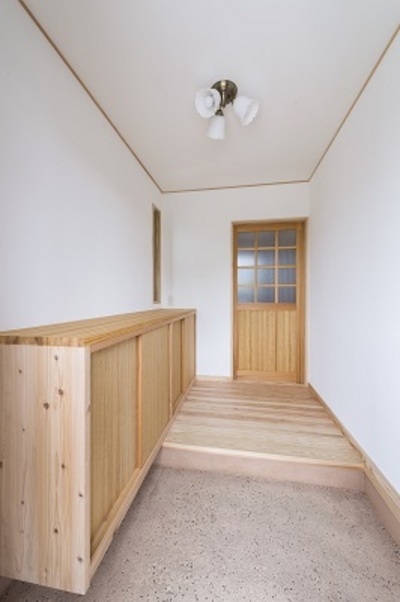 靴箱はたっぷりと収納できるように造作。濃紺の玄関ドアを入ると木の香りが漂う。