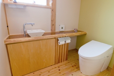 トイレ。杉の一枚板をカウンターに設置。一面のみをうぐいす色にした壁が楽しい。