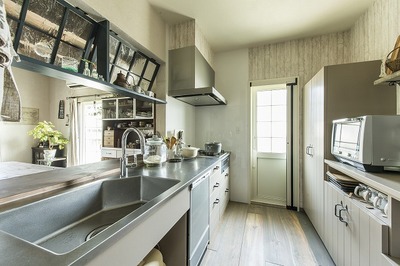 オリジナルキッチンは、天板もステンレスで“使い込まれた風”に加工した。シンク上の吊り棚もオリジナル。“雨ガラス”の表情が素敵。格子ガラスは桟の数や太さにもこだわりました。好きなものに囲まれて台所仕事も楽しくなりそう。