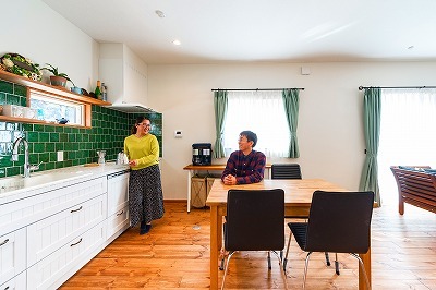 壁に面したキッチンでダイニングにゆとりの空間が生まれた。
木製キッチンは、奥様お気に入りのグリーンのタイルがポイント。