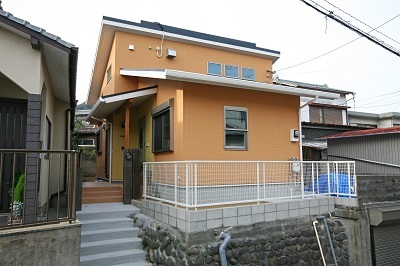 鮮やかなオレンジの外観。南側の屋根にはＯＭソーラーの集熱パネルが設置されています。