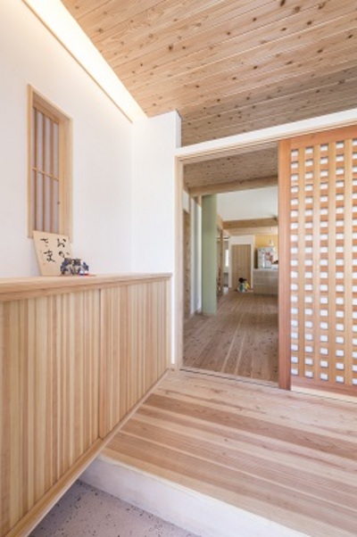 端正な佇まいの玄関。リビングに通じる格子の扉は美しい。反対側にはアウトドア用品も置ける土間収納を設置。