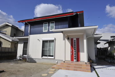 奥さまのご希望で、赤い玄関扉と樋が効果的なアクセントになっている紺・白のツートンのお家です。