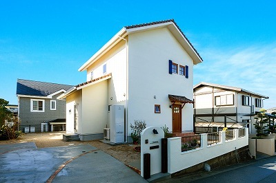 ブルーの窓飾りがアクセントの外観。S字瓦に塗り壁の外壁、木製の玄関ドアや窓もコティの標準仕様。