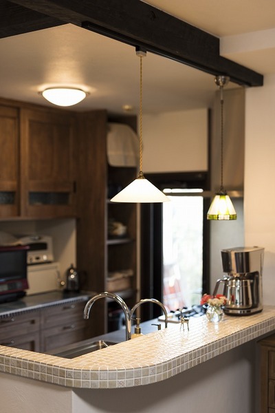 料理上手な奥さまに、収納物も細かく採寸して無駄のないオーダーキッチンを提案した。後のカップボードもリビングの雰囲気に合わせて無垢材で造作。目隠しカウンターの角を丸くしタイル張りすることで優しい印象に。お気に入りのレトロな照明も一つ一つ慎重にセレクト。 料理上手な奥さまに、収納物も細かく採寸して無駄のないオーダーキッチンを提案した。後のカップボードもリビングの雰囲気に合わせて無垢材で造作。目隠しカウンターの角を丸くしタイル張りすることで優しい印象に。お気に入りのレトロな照明も一つ一つ慎重にセレクト。