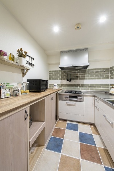 ダイニングの横にはアーチ入口のキッチン。床・壁に鮮やかなタイルを。L型のキッチンをシステムキッチンに一新し、機能性アップ。