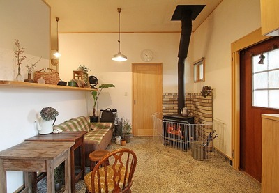 扉を開けると目に飛びこんでくるのは、広い土間とそこに置かれた薪ストーブ。<br />
リフォームをする上で一番悩まれたのは、『薪ストーブ』の場所。<br />
掃除のしやすさや汚れても気にならない点から玄関に置くことに。