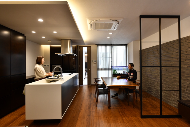 イメージはホテルの空間。落ち着いたダークブラウンの色合いと、無機質なホワイトをメーンカラーにしました。壁画にはレンガを貼り、落ち着いた空間になるようにダウンライトと間接照明にして柔らかい雰囲気を出しています。住環境も一つのテーマでしたからペアサッシや床暖房にしています。