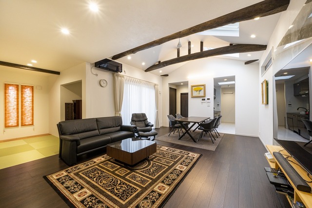 トップライトから光が届く、開放的なリビング。インテリアは白とダークブラウンを基調とした落ち着いた雰囲気に。堂々とした構造梁にはアンティーク塗装を施して現しに。ダイニングテーブルは以前の家で使っていた座卓に艶消し塗装をかけてリメイク。随所に古い家の名残を感じることができる